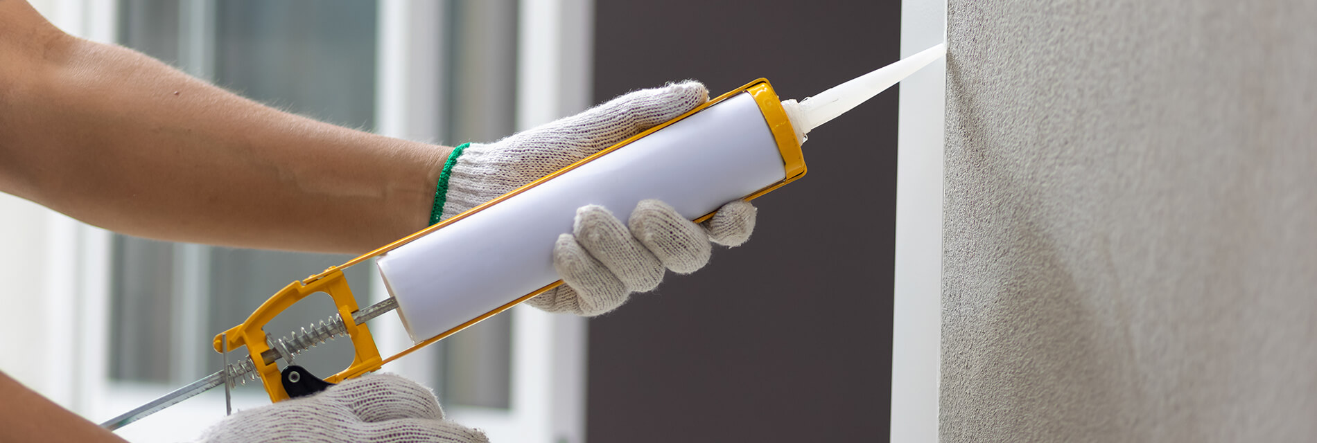 Construction worker using silicone sealant caulk the outside win