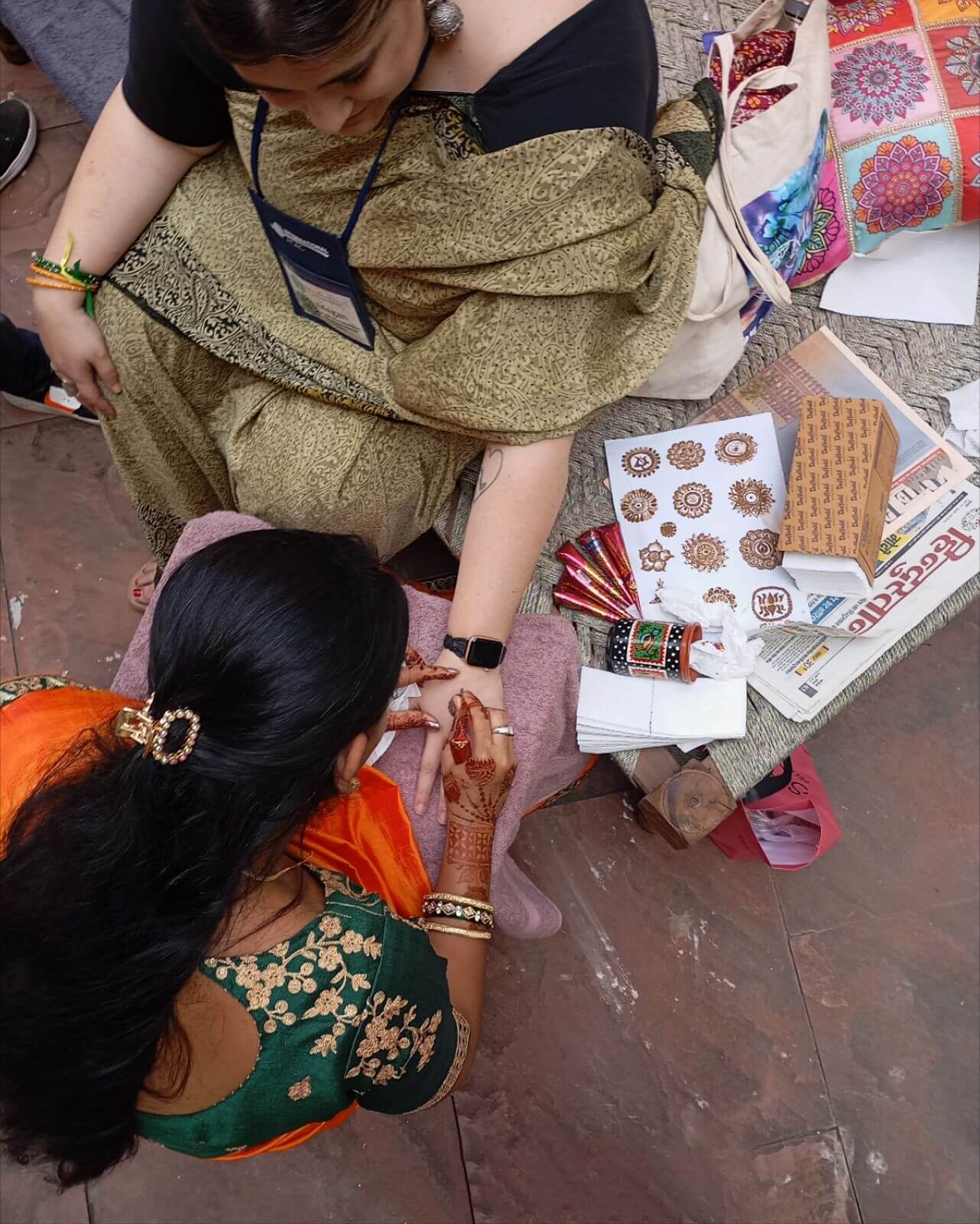 A woman getting a mendhi design drawn on her hand.