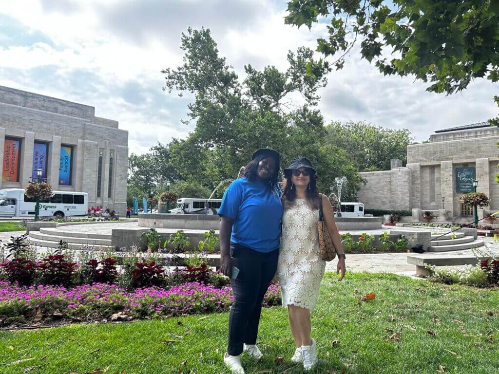 Two women standing on a lawn in front of a university building