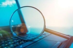 Laptop computer with magnifying glass, concept of search
