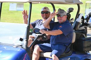 2 guys in a golf cart waving