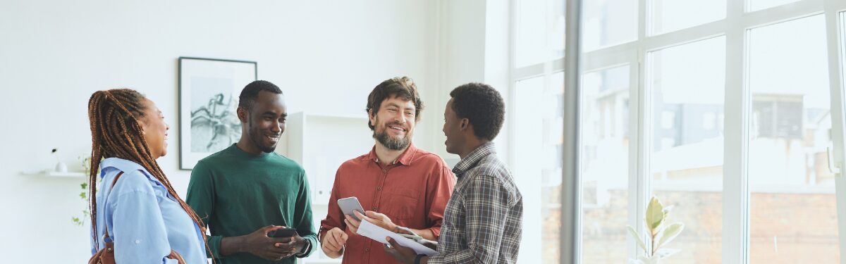 Group of people standing in casual office setting smiling.