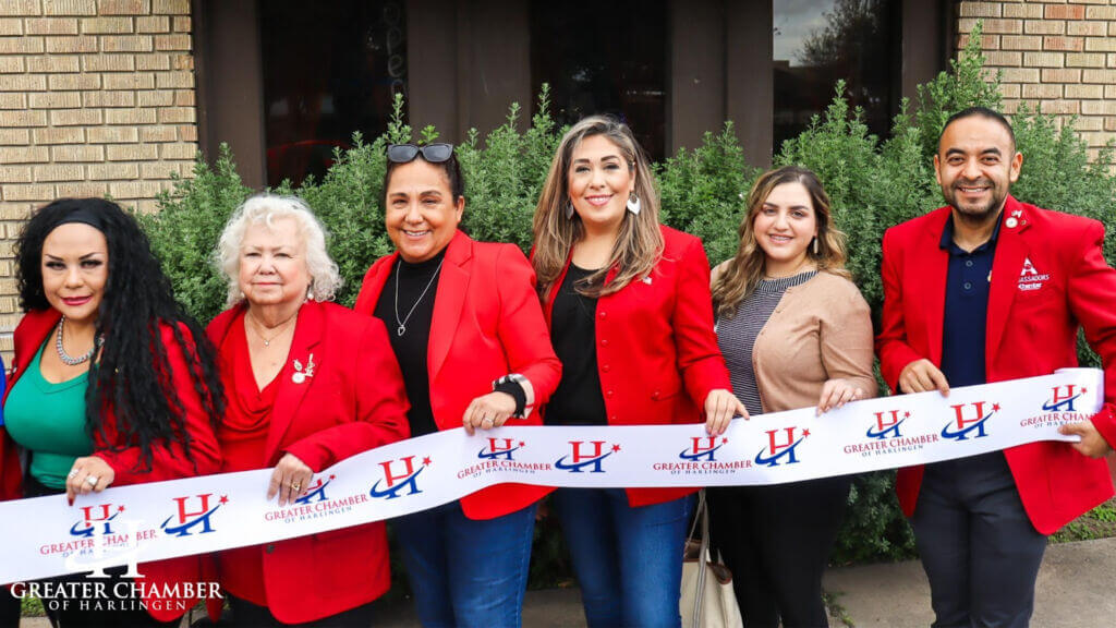 People holding a ribbon with the logo of the Greater Chamber of Harlingen

