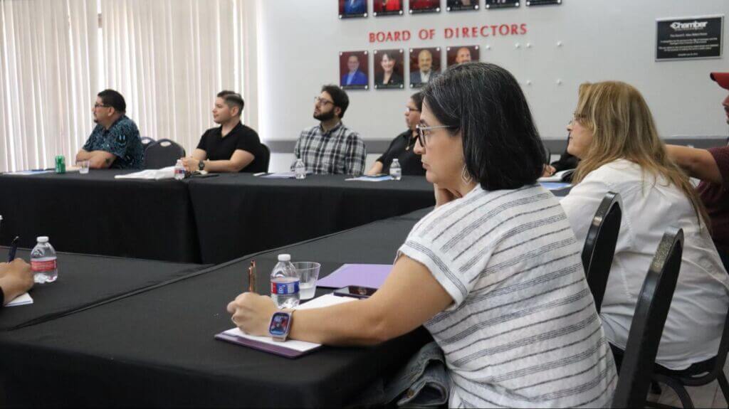 A group of people sitting at a long table covered with black tablecloths