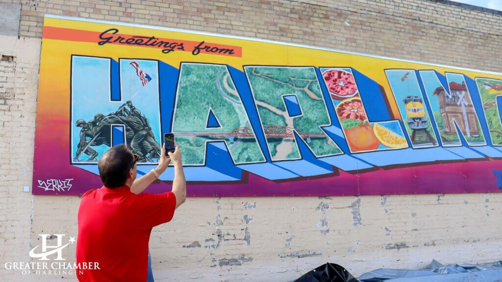 person taking a photo of a mural in Harlingen artist Adrian Rodriguez, representing some of the things to do in Harlingen TX