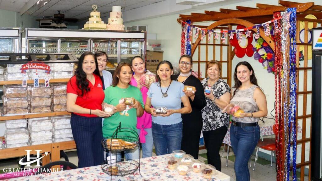Local business owners in Harlingen showcasing baked goods during a community Chamber event.