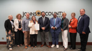 Left to right: Commissioner Shirley Allenbrand (6th District), Commissioner Julie Brewer (3rd District), Chamber Board Member Zach Rose-Heim, Chamber Board President Kate Nielsen, Johnson County Board Chair Mike Kelly, Chamber Board Vice President Jay Bohanon, Chamber Executive Director Tracey DeMarea, Commissioner Janee Hanzlick (4th District), and Commissioner Jeff Meyers (2nd District) pose for a photo following the official proclamation of June 2025 as Pride Month in Johnson County.