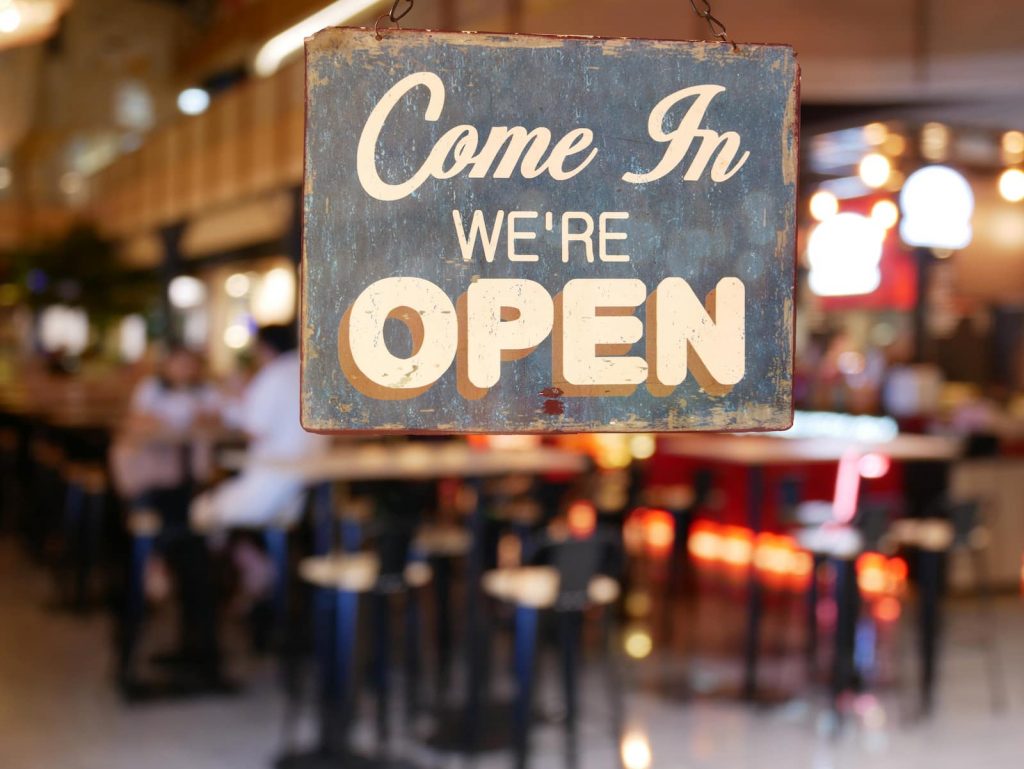 come in we're open sign hanging on a window