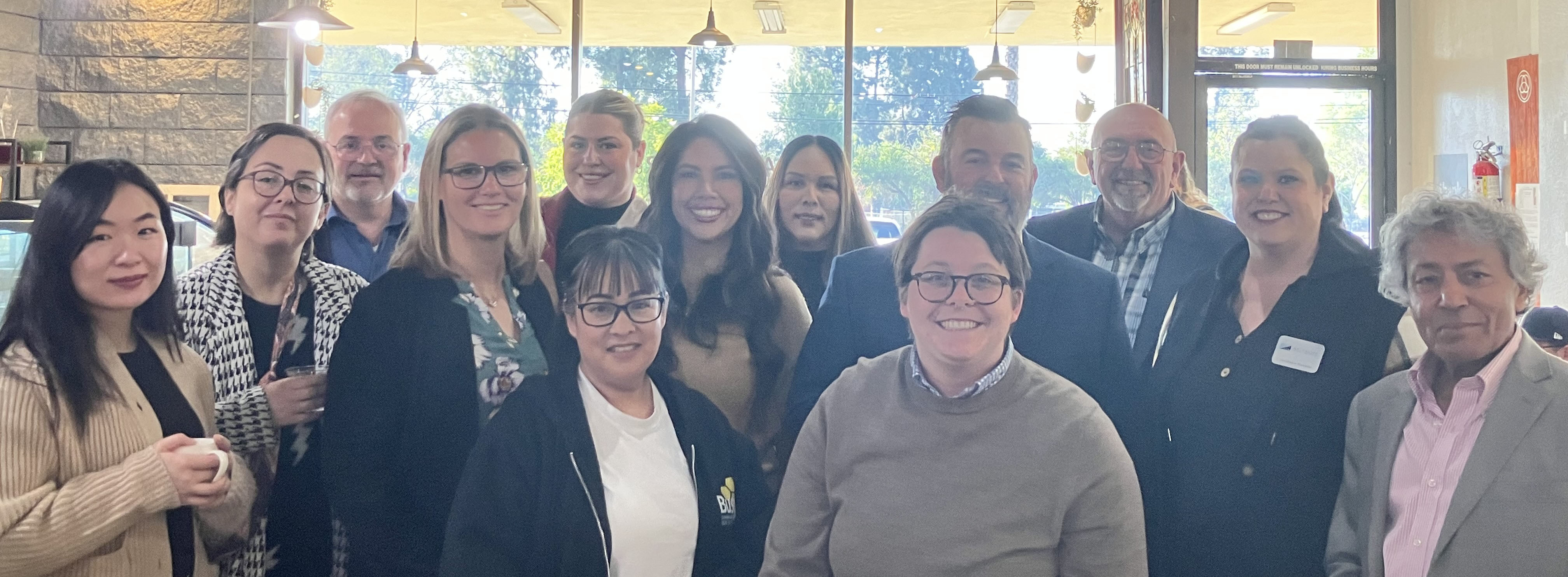 a group of Chamber Members and Staff standing and smiling for the camera at the Chamber event Network and Sip