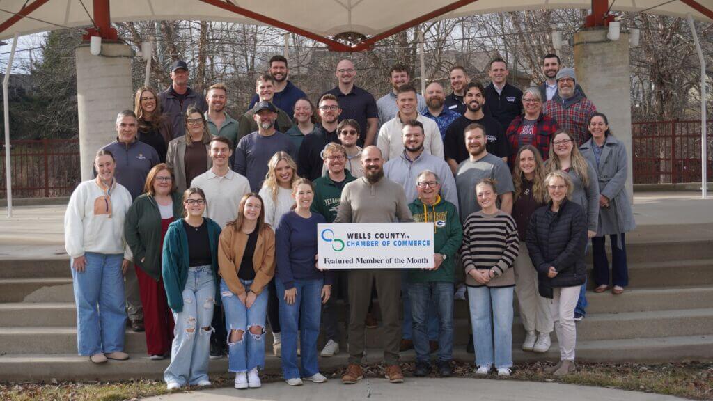 A photo of the staff with BIGJAWS Youth for Christ, holding up a sign with the Wells County Chamber logo that says "Featured Member of the Month."