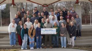 A photo of the staff with BIGJAWS Youth for Christ, holding up a sign with the Wells County Chamber logo that says "Featured Member of the Month."
