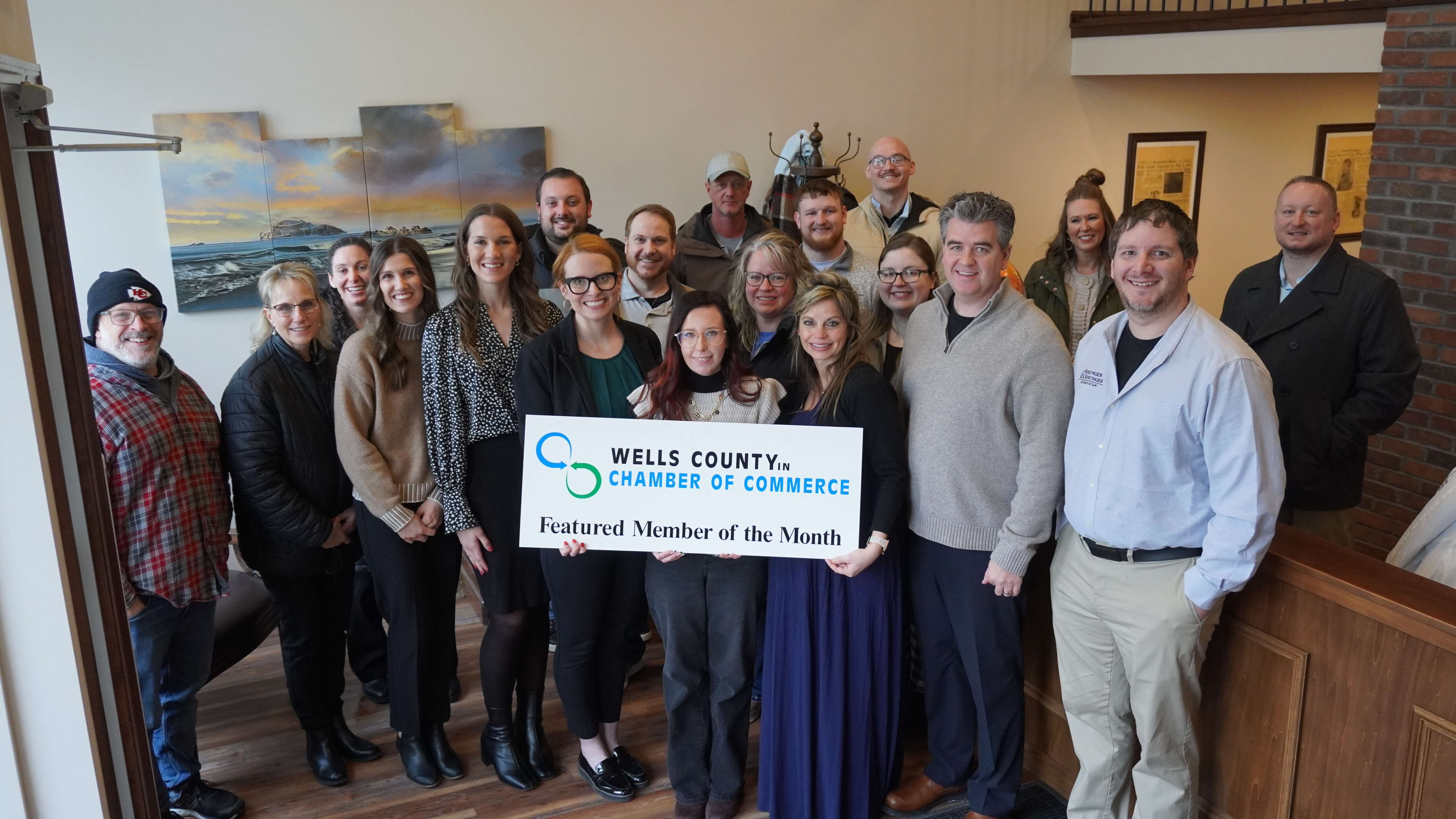 Sprunger and Sprunger MOTM A group photo consisting of employees of Sprunger & Sprunger, the Wells County Chamber, Chamber Ambassadors. They are holding up a sign reading, "Wells County Chamber of Commerce, Featured Member of the Month."