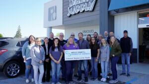 A group photo of chamber staff, ambassadors, and staff of Dazey's Supply in Bluffton, Indiana holding a Member of the Month sign outside the storefront.