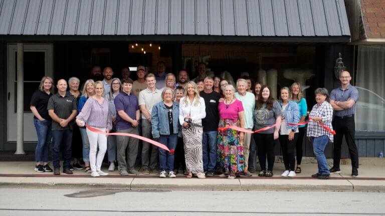 A ribbon cutting for The Vault in Markle, IN taking place outside the front of the building. Pictured are Chamber staff, Chamber Ambassadors, The Vault staff, and community members.