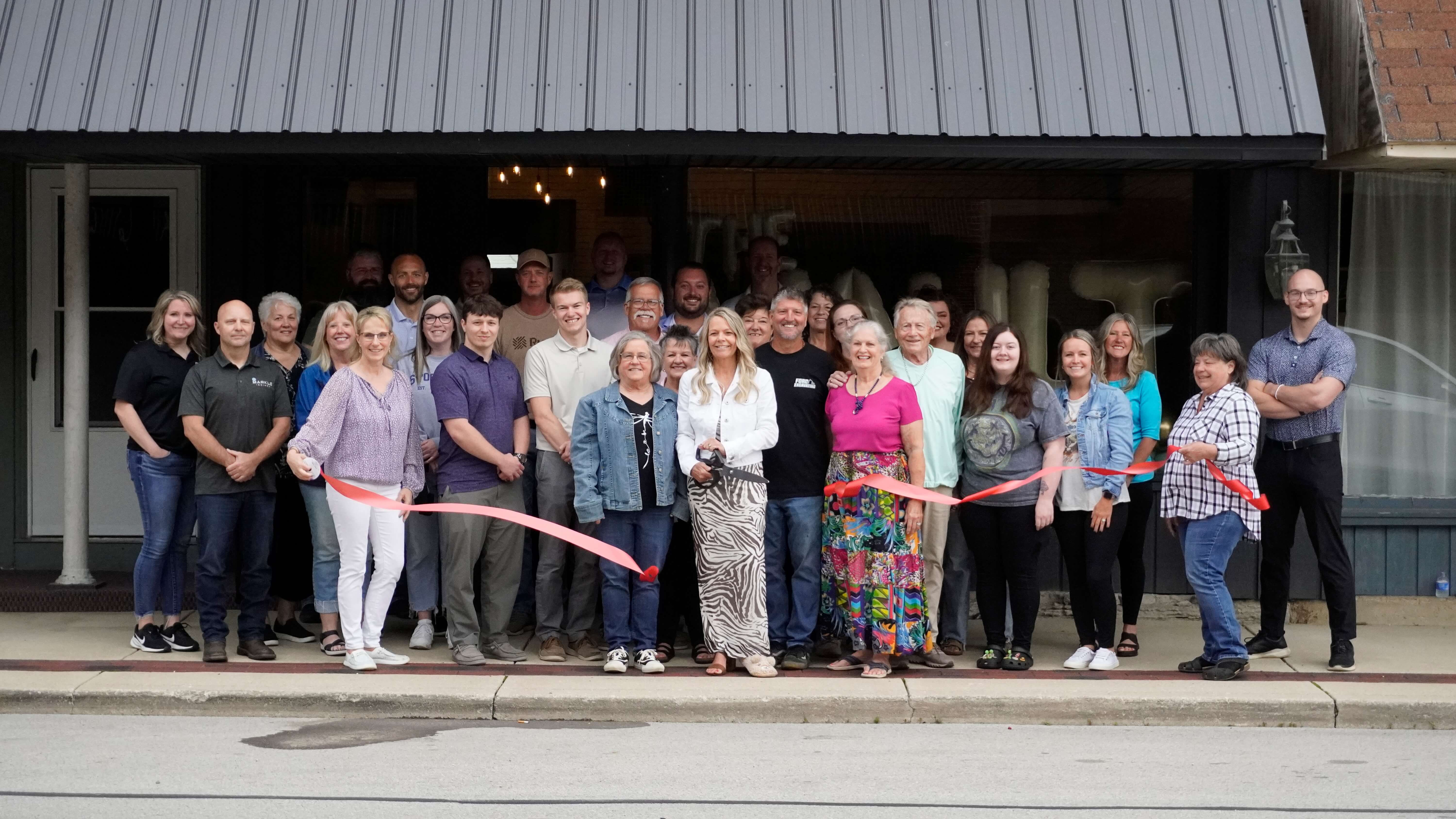 A ribbon cutting for The Vault in Markle, IN taking place outside the front of the building. Pictured are Chamber staff, Chamber Ambassadors, The Vault staff, and community members.