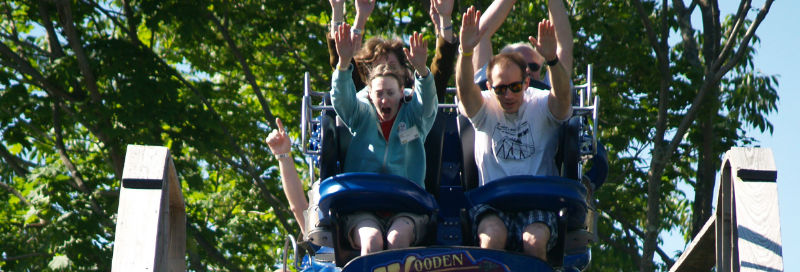 people with hands in the air on roller coaster