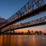 Crescent City Connection at sunset with New Orleans skyline in background.