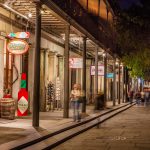 After dark, shops in the French Quarter are lit up with people walking on the sidewalks and streets.