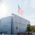 National World War II Museum exterior of building with American flag flying in front of building.