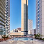 New Orleans Marriott exterior photo between two towers, on the 5th floor, photo shows the rooftop pool and orange lounge chairs with a blue sky and buildings in the background.