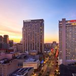 Sunset view of Canal Street in New Orleans picturing the New Orleans Marriott on the right and Sheraton New Orleans on the left, just across the street from the New Orleans Marriott.