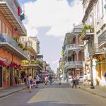 Royal Street in New Orleans photo shows colorful buildings, banisters, awnings, stores and people walking
