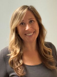 Amanda Copes headshot, woman, long blond curled hair, gray blouse