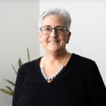 Wendy Chase headshot, woman with short gray hair, black rimmed glasses, black blouse