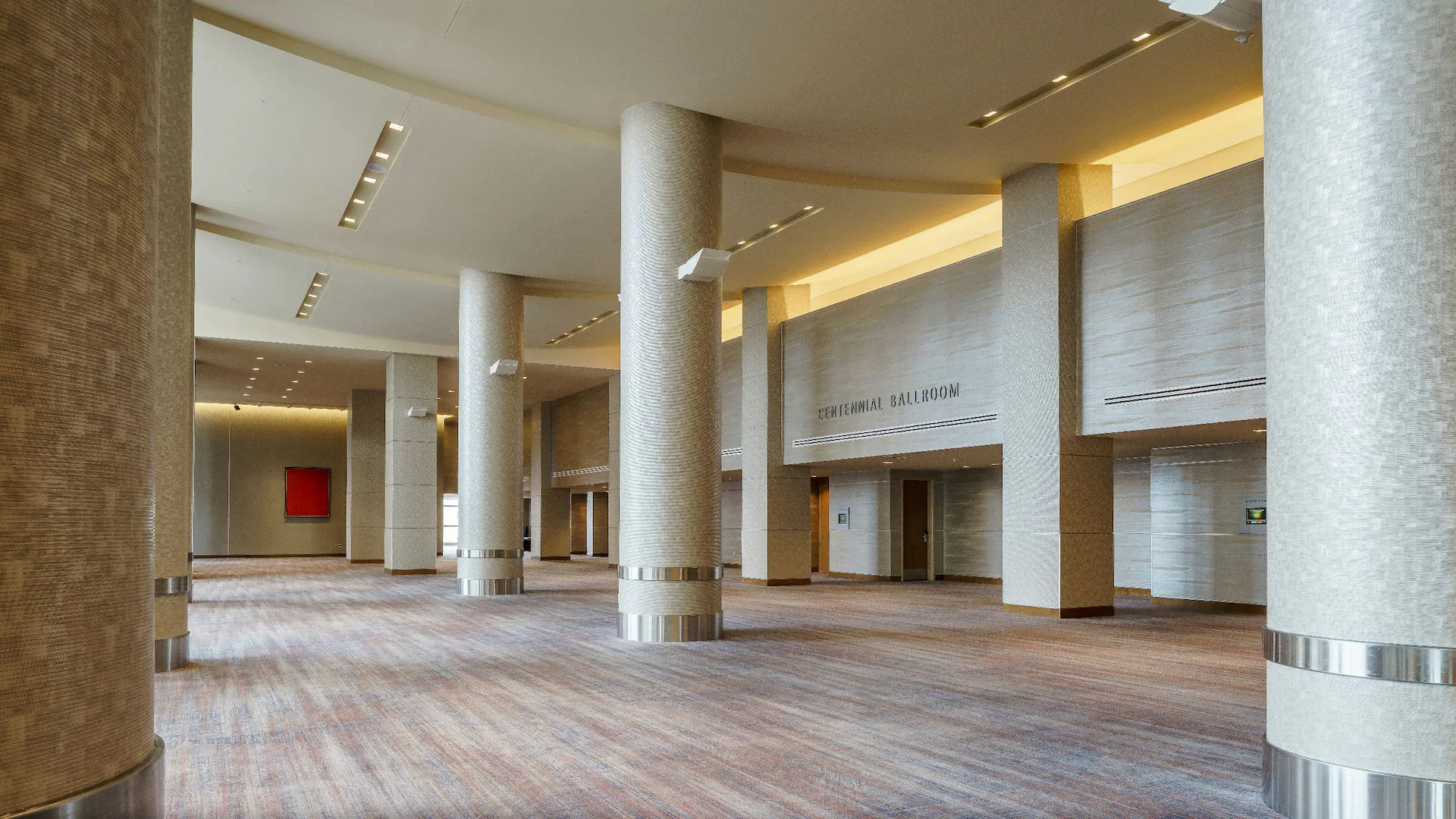 Carpeted prefunction space outside of meeting room with multiple columns