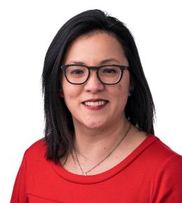 Woman with shoulder-length brown hair, smiling, wearing dark rimmed glasses and red blouse