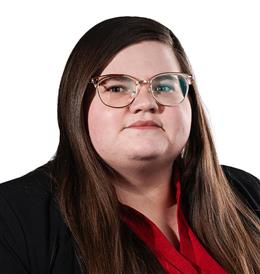 Woman with long, straight, brown hair, wearing glasses, smiling, earing red blouse, and black blazer
