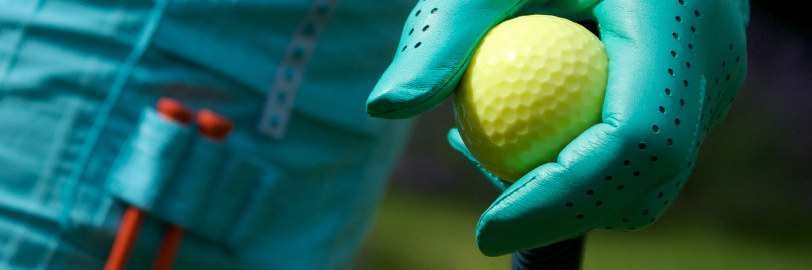 An up close image of a gloved hand placing a golf ball on top of a tee