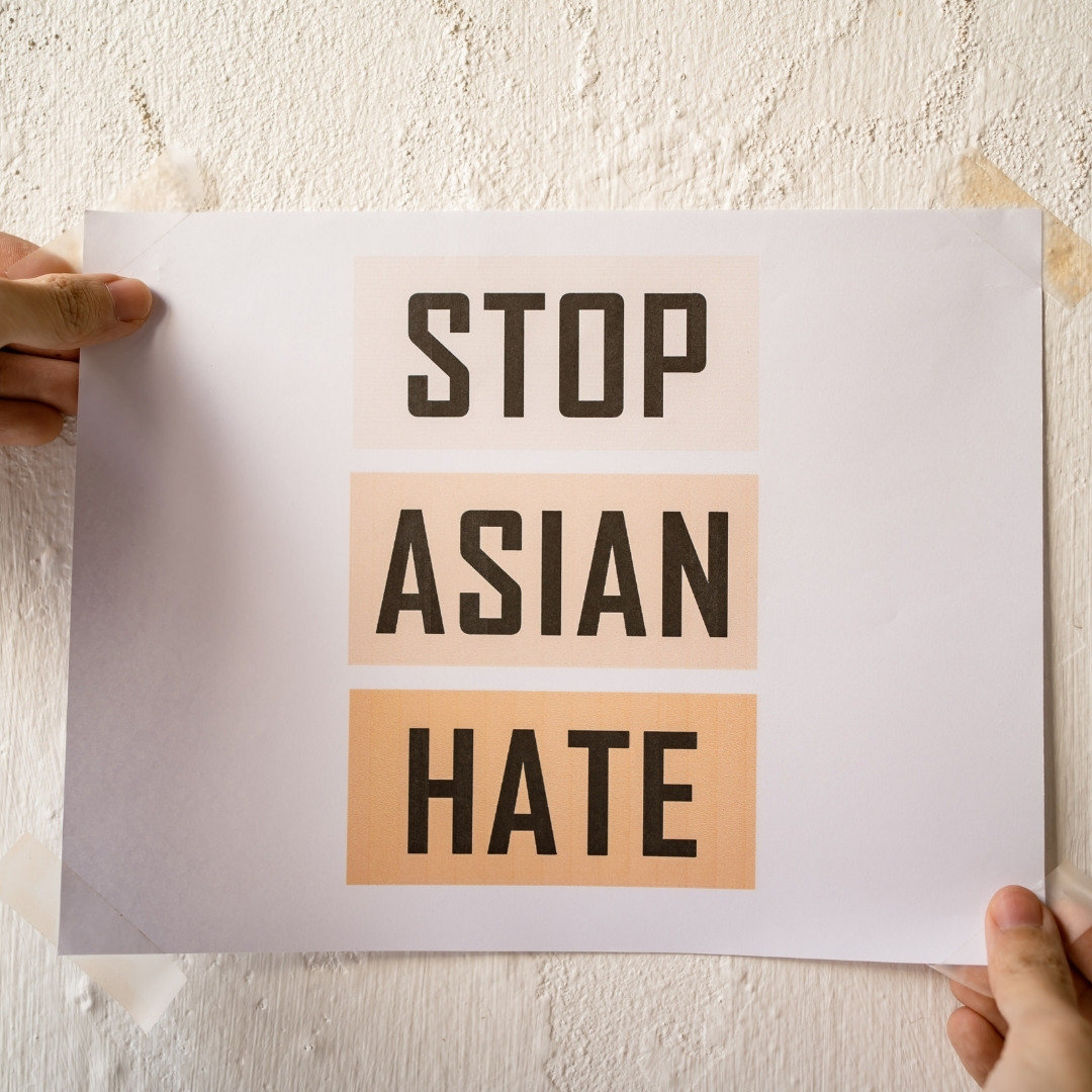 A white person posting a sign that reads, "Stop Asian Hate"