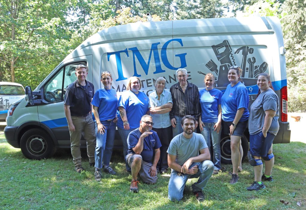 The volunteer team poses with the veteran and his family in front of a company van.