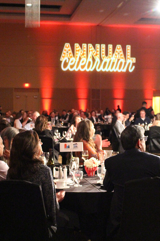 Attendees at Annual Celebration table watching entertainment on stage