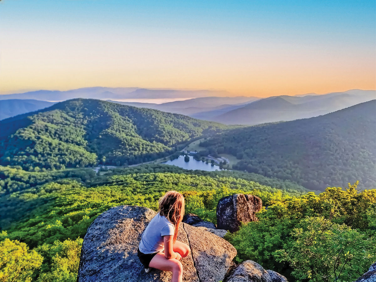 A young hiker overlooks Abbott Lake from atop Sharp Top Mountain at Peaks of Otter.