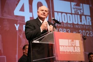 Roland Brown discursa para a multidão no World of Modular 2023 após sua inclusão no Hall da Fama do setor de construção modular da MBI.