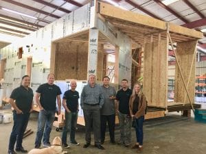 Group of people standing in front of an unfinished construction project inside a factory