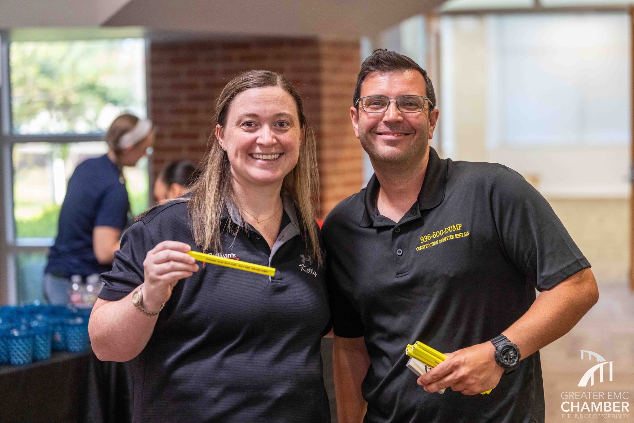Kelly stands with Joe Crosby at a Monthly Luncheon, showing off promotional swag.