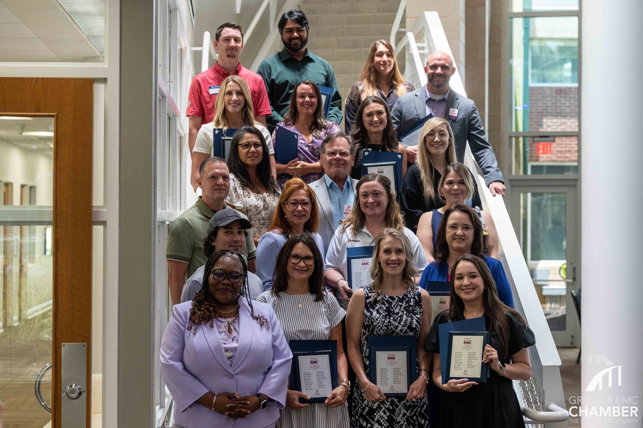 Class of 2026 graduates of Pathway to Leadership EMC stand for the iconic graduation photo on the stairs in the Atrium Center.