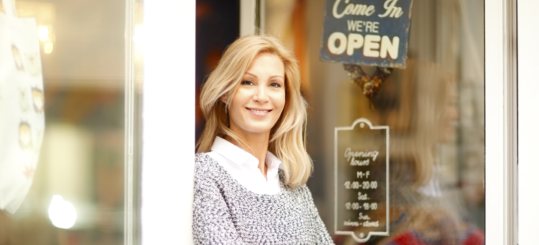 Female business owner in front of her open store.