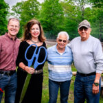 younger and older couple posing with large scissors
