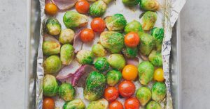 Brussel sprouts, tomatoes and red onions roasting on a sheet pan