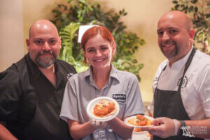 Two men and a woman holding small plates of food