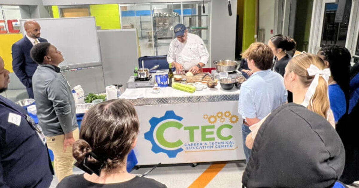 A group of people watch a chef demonstrating cooking food.