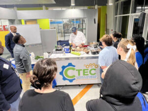 A group of people watch a chef demonstrating cooking food.