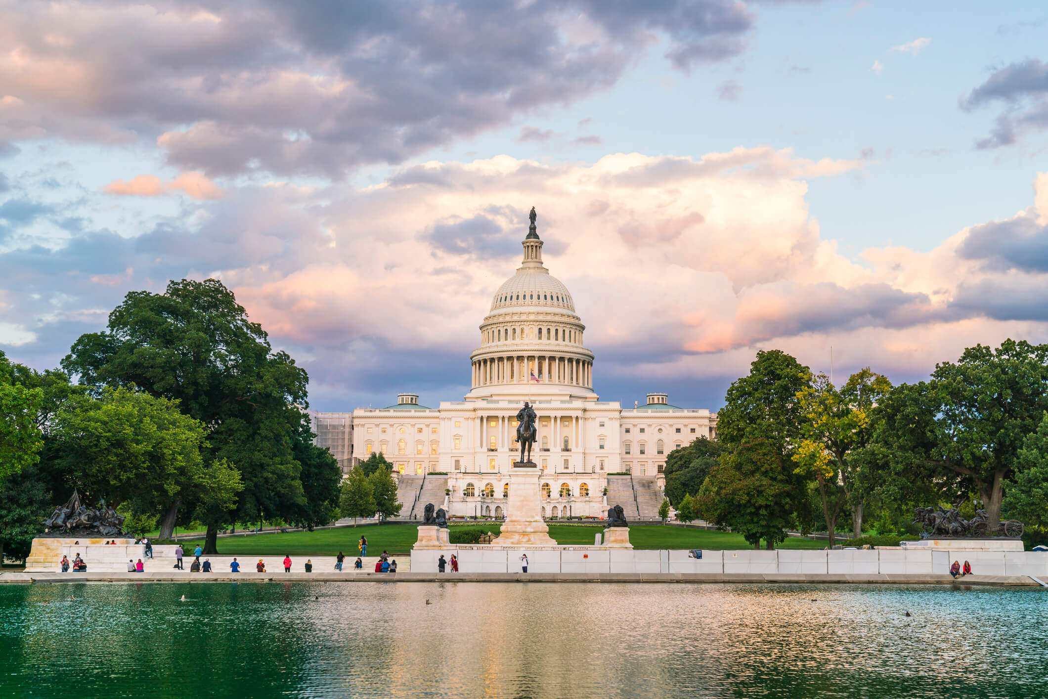 The United States Capitol building at sunset wirh reflection in water.