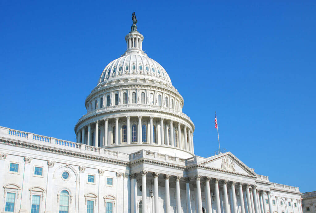 White United States Capitol building with a large dome and a clear blue sky