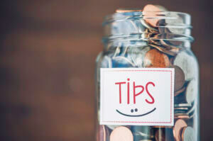 Tip jar with American currency on brown background.