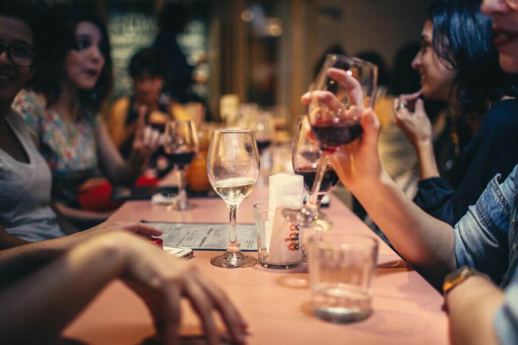 Guests dining in restaurant holding drinkware.